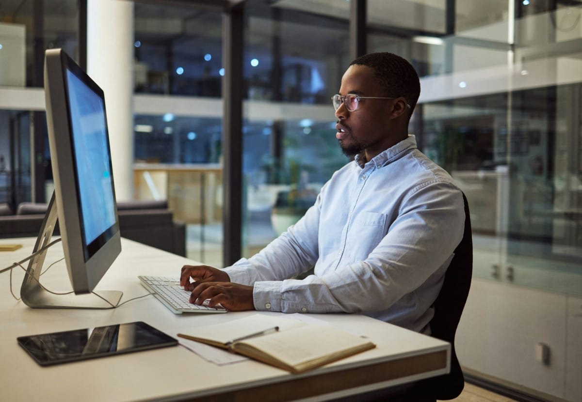 Businessman typing on computer with internet analytics in an office at night. Professional entrepre